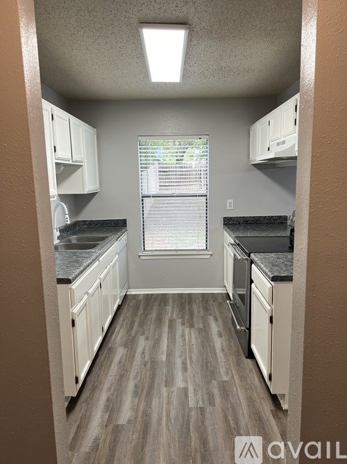 A kitchen with white cabinets and a black countertop.