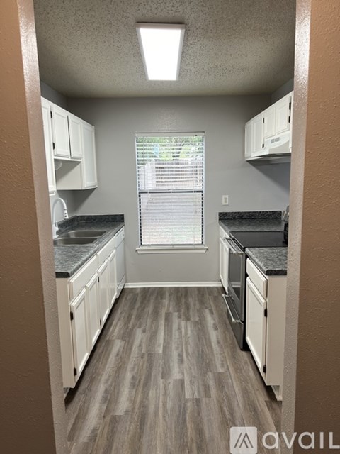 A kitchen with white cabinets and a black countertop.