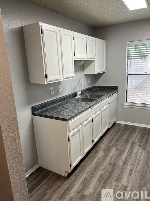 A kitchen with white cabinets and a granite countertop.