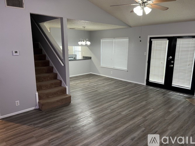 A spacious room with a staircase and a ceiling fan.