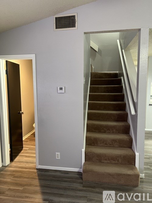 A staircase with a carpeted runner and a wall-mounted air vent.
