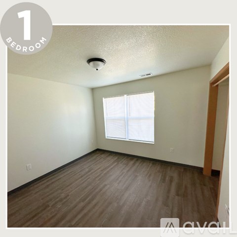 A bedroom with a window and wooden flooring.