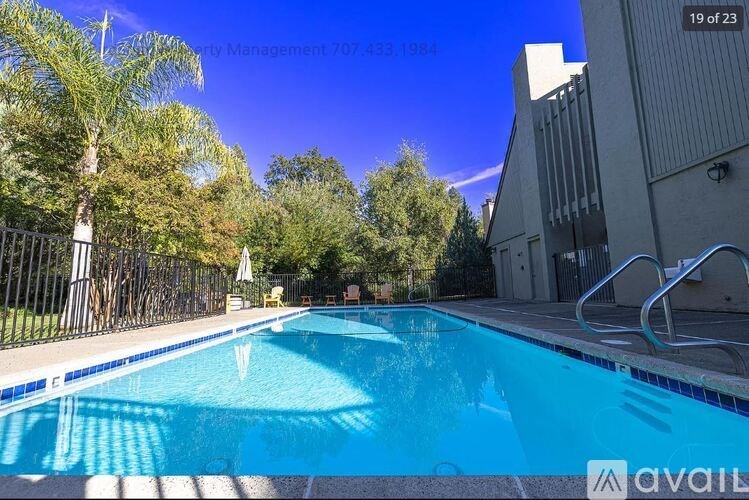 A swimming pool surrounded by trees and a building in the background.