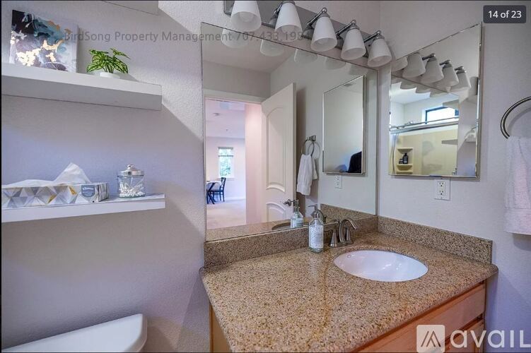 A bathroom with a sink, mirror, and a towel hanging on the door.