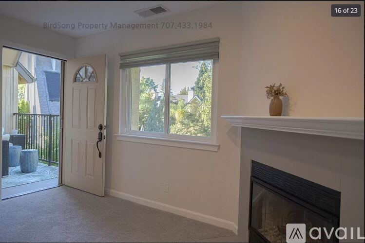 A room with a fireplace and a window with a view of trees.