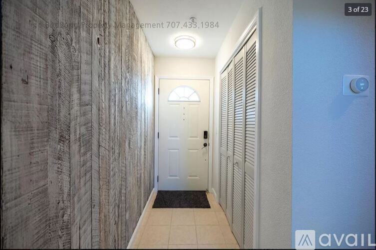 A hallway with a door at the end and a textured wall on the left.