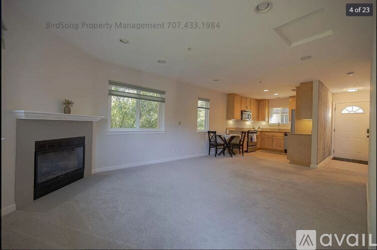 A living room with a fireplace and a dining area in the background.