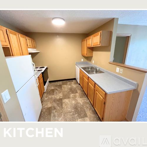 A kitchen with a white fridge, wooden cabinets, and a tiled floor.