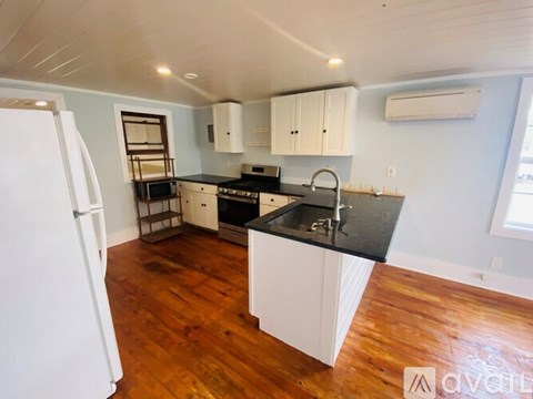 A kitchen with white cabinets and black countertops.