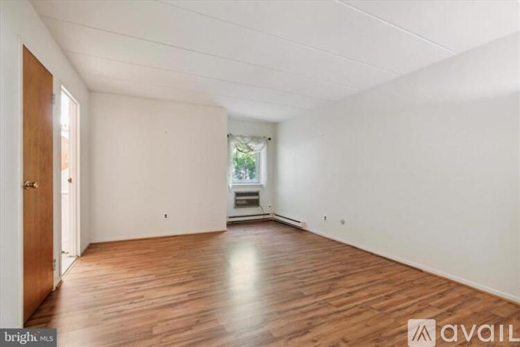 A spacious room with wooden flooring and white walls.