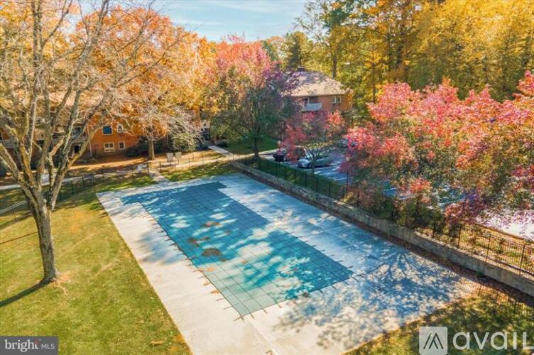 A brightly lit swimming pool surrounded by trees and a house.