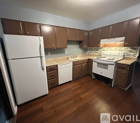 A kitchen with brown cabinets and a white fridge.