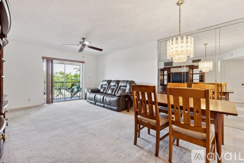 A living room with a black leather couch and a wooden dining table.
