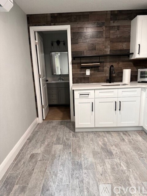 A kitchen with white cabinets and a wooden backsplash.