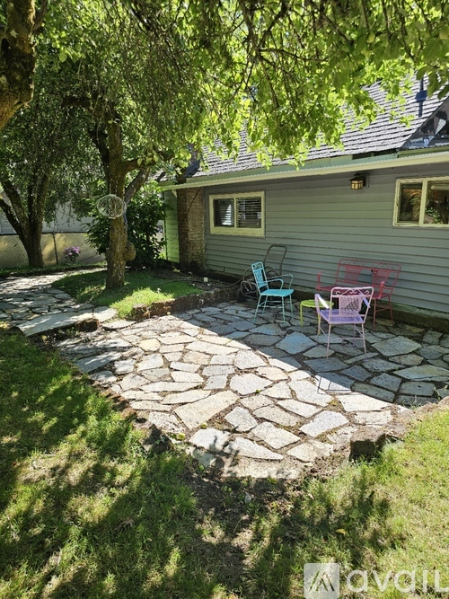 A patio with a stone walkway and two chairs.
