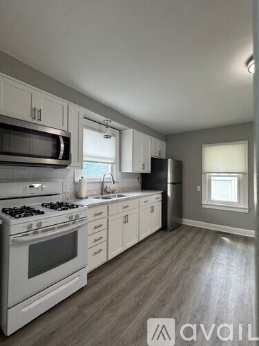 A kitchen with white cabinets and a stove top oven.