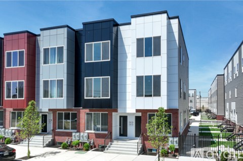 A row of modern townhouses with a car parked in front of the first one.