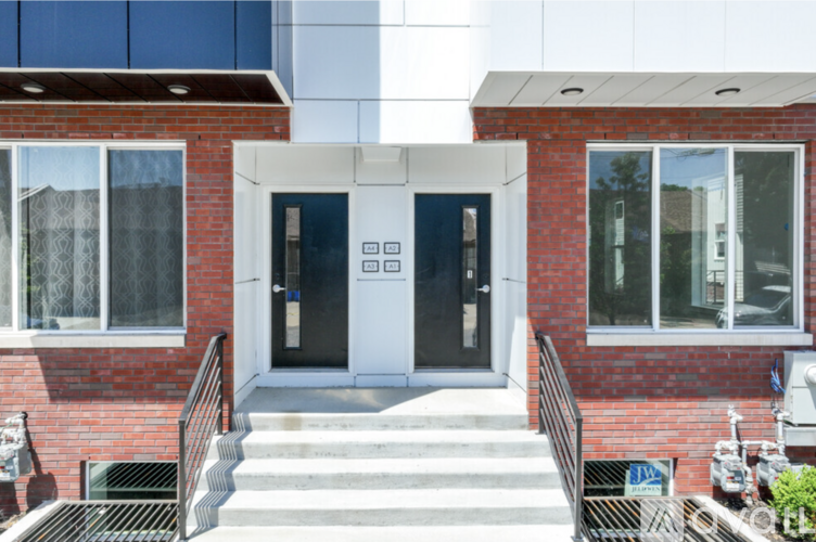 A red brick building with a white door and steps leading up to it.