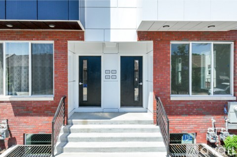 A red brick building with a white door and steps leading up to it.