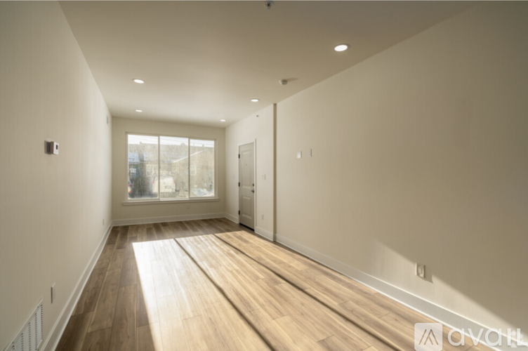 A long, empty hallway with wooden floors and white walls.