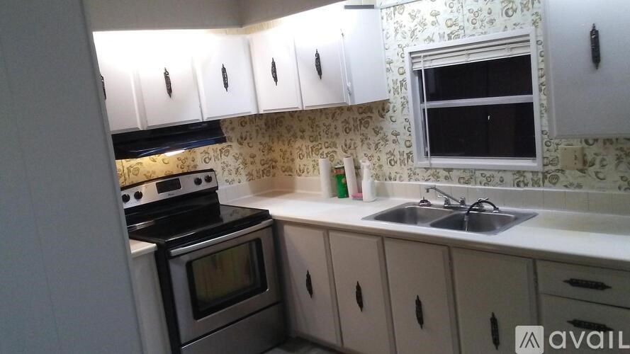 A kitchen with a stove, oven, sink, and cabinets.