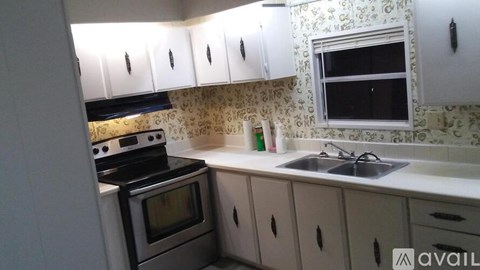 A kitchen with a stove, oven, sink, and cabinets.