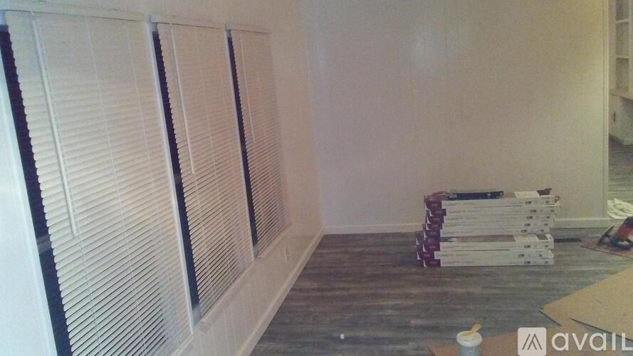 A room with a white wall and a window covered with blinds.