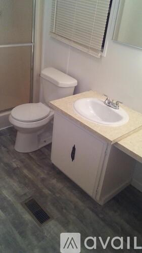 A bathroom with a toilet, sink and a cabinet.
