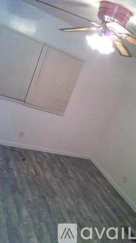 A room with a ceiling fan and a window with blinds.