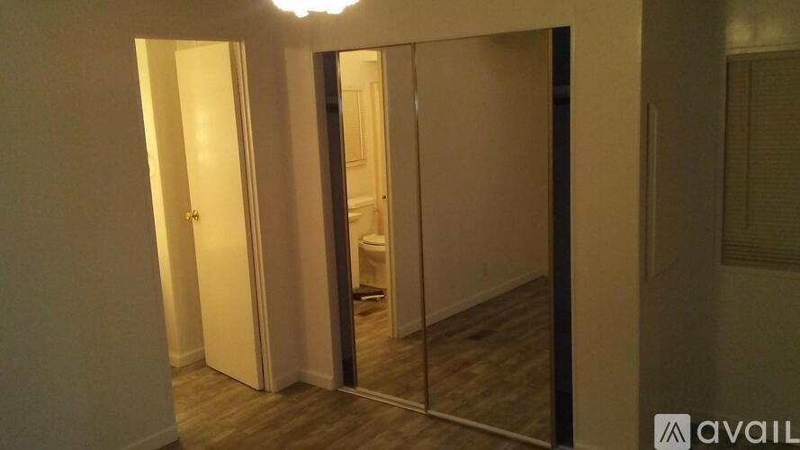 A room with a mirrored door and a wooden floor.