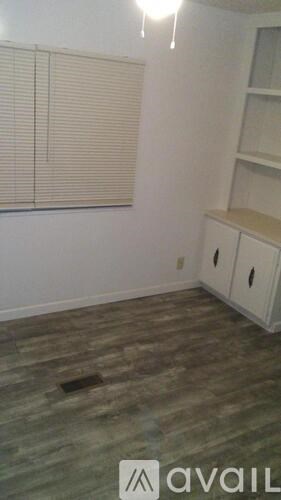 A room with wooden flooring and a window with blinds.