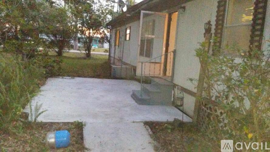 A small house with a concrete patio surrounded by greenery.