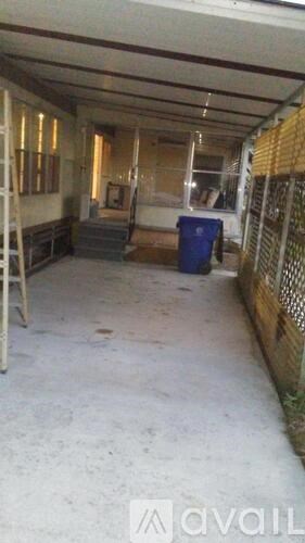 A long, narrow, unfinished room with a blue bin and a ladder.