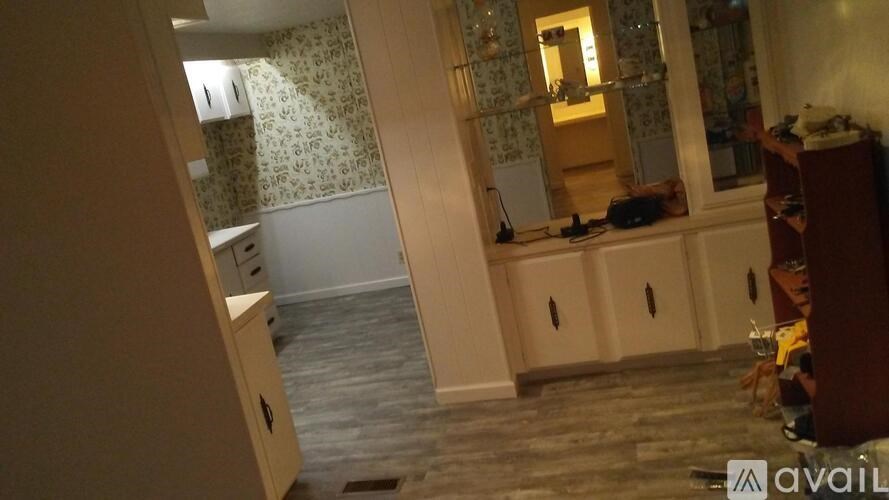 A room with a patterned wallpaper and a wooden cabinet.