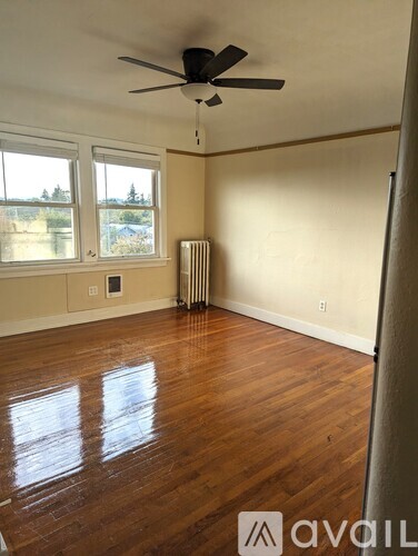 A room with a ceiling fan and hardwood floors.