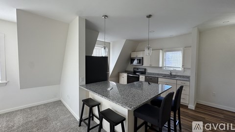A kitchen area with a granite countertop and bar stools.