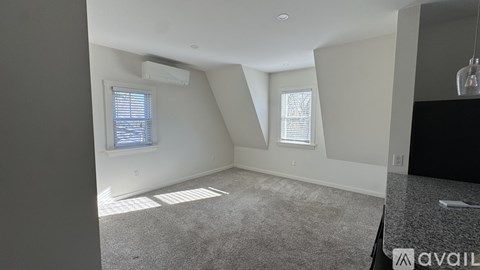 A room with a carpeted floor and two windows.