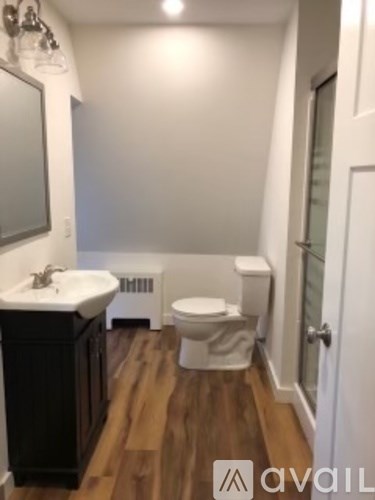 A bathroom with a toilet, sink, and mirror.