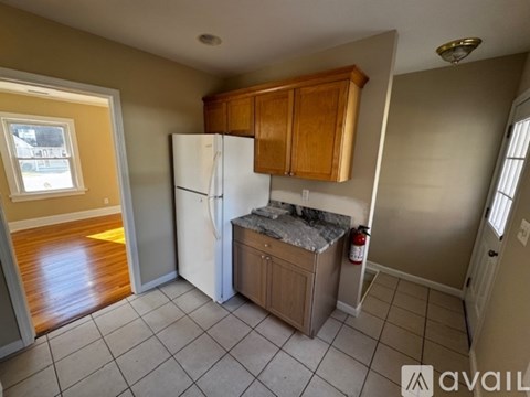 A kitchen with a white refrigerator and wooden cabinets.