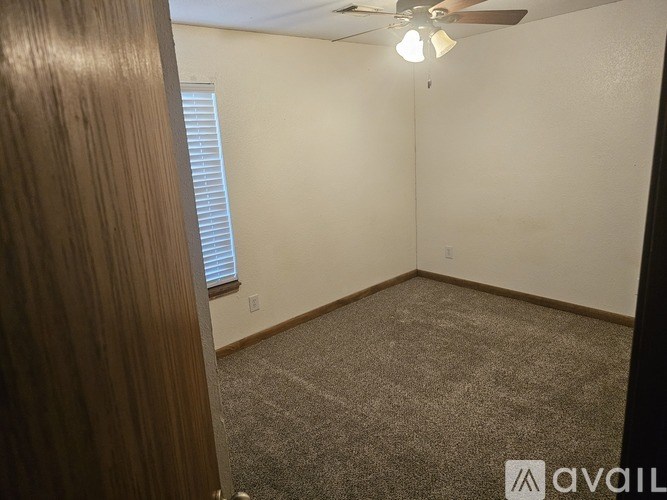 A room with a carpeted floor, a ceiling fan, and a window with blinds.
