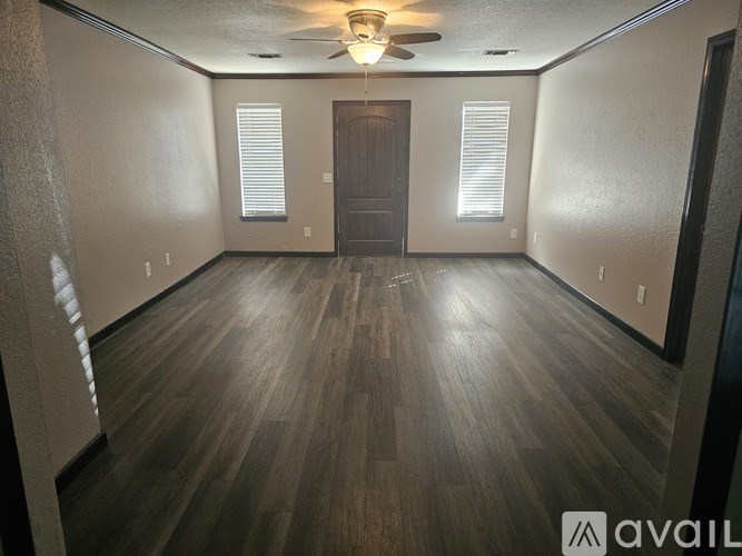 A spacious room with wooden flooring and a ceiling fan.
