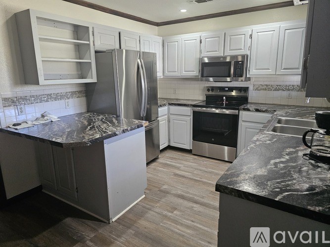 A kitchen with a granite countertop and stainless steel appliances.