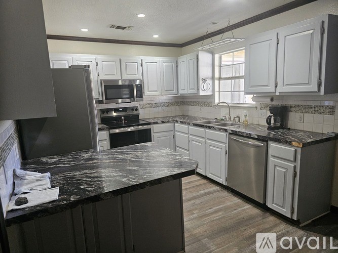 A kitchen with a black countertop and stainless steel appliances.