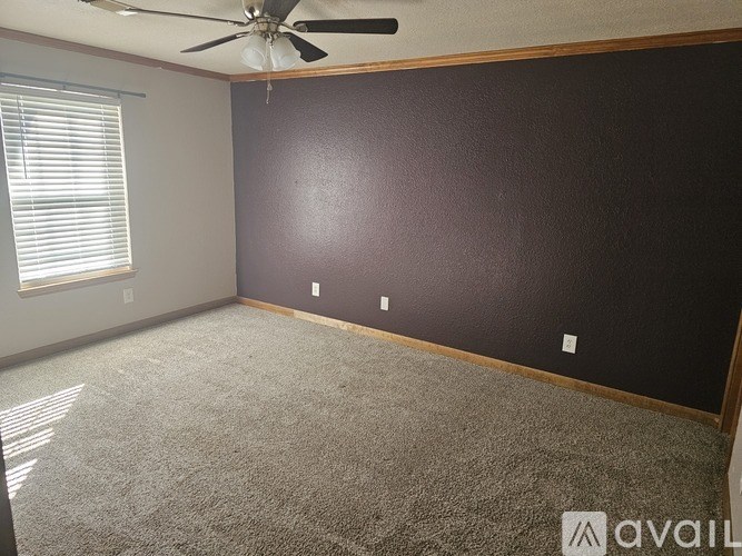 A room with a ceiling fan and a window with blinds.