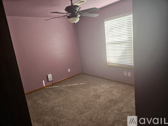 A room with a ceiling fan and a window with blinds.