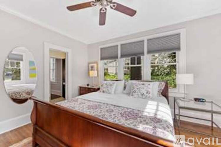 A bedroom with a bed, a ceiling fan, and a nightstand with a lamp.