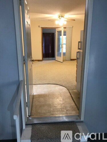 A hallway with a carpeted floor and a ceiling fan.