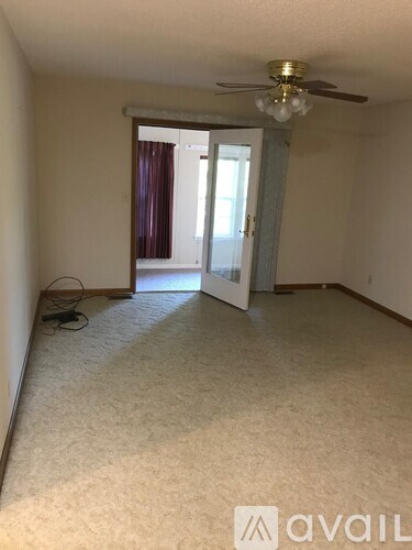 A room with a carpeted floor and a ceiling fan.