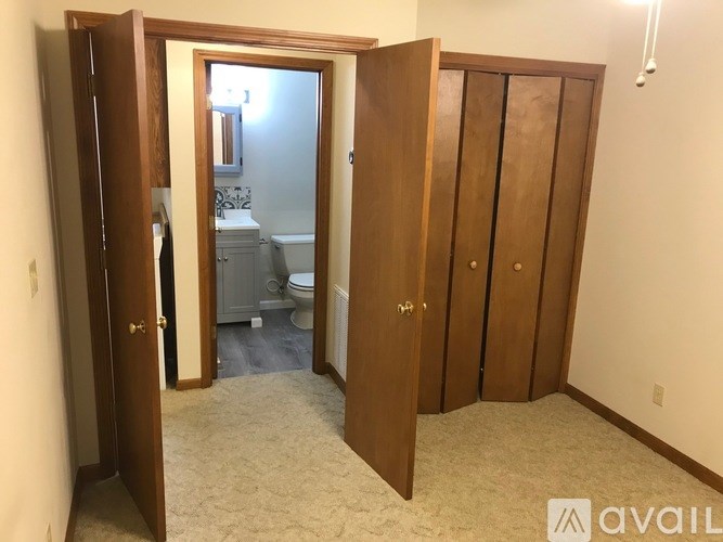 A room with a carpeted floor and a bathroom visible through an open door.