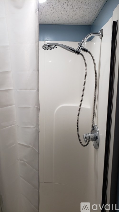 A white shower stall with a shower head and hose.